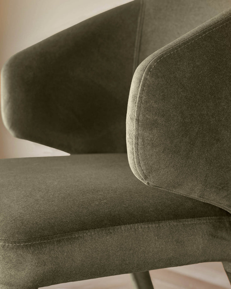 Close-up of a stylish olive green armchair, showcasing its textured fabric and cushioned armrest.