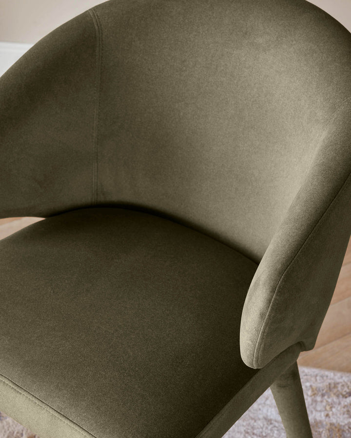 Close-up of a stylish olive green upholstered chair, showcasing its modern design and comfortable look.
