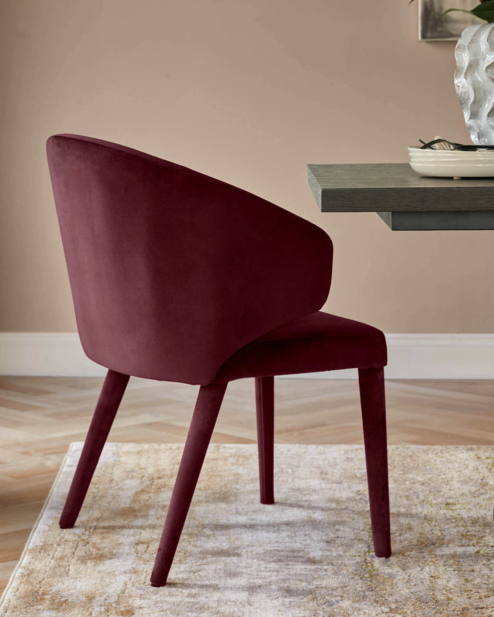 Ethan dining chair in plum velvet, shown from rear angle with wooden legs on a neutral rug.
