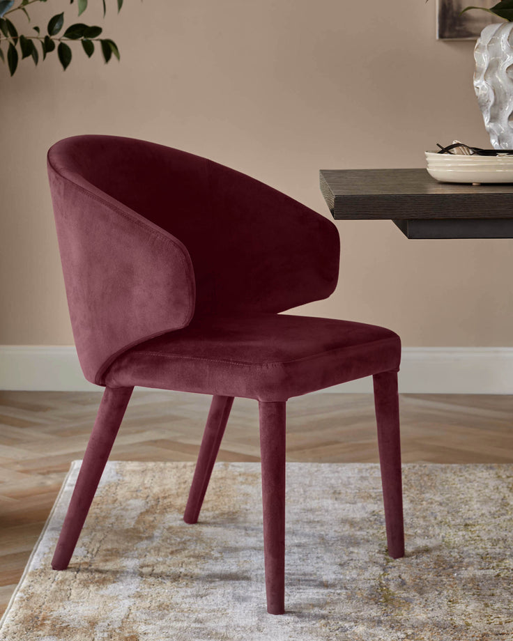 Plum velvet dining chair with curved backrest and four wooden legs, positioned at an angle in a styled room setting.