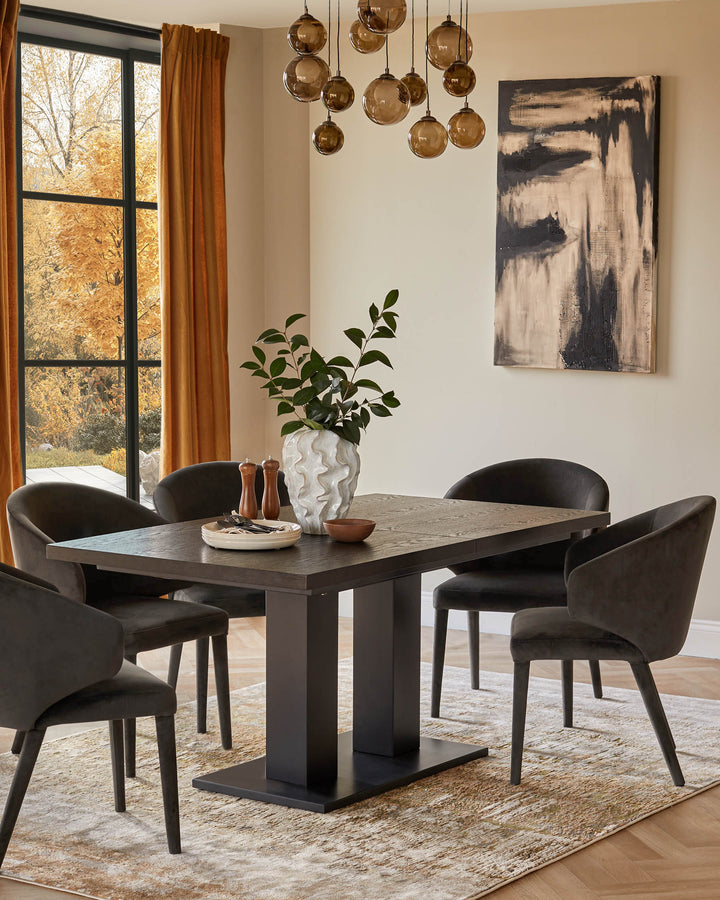 Dining table with four chairs, decorative vase and overhead lighting in a stylish, neutral dining room.