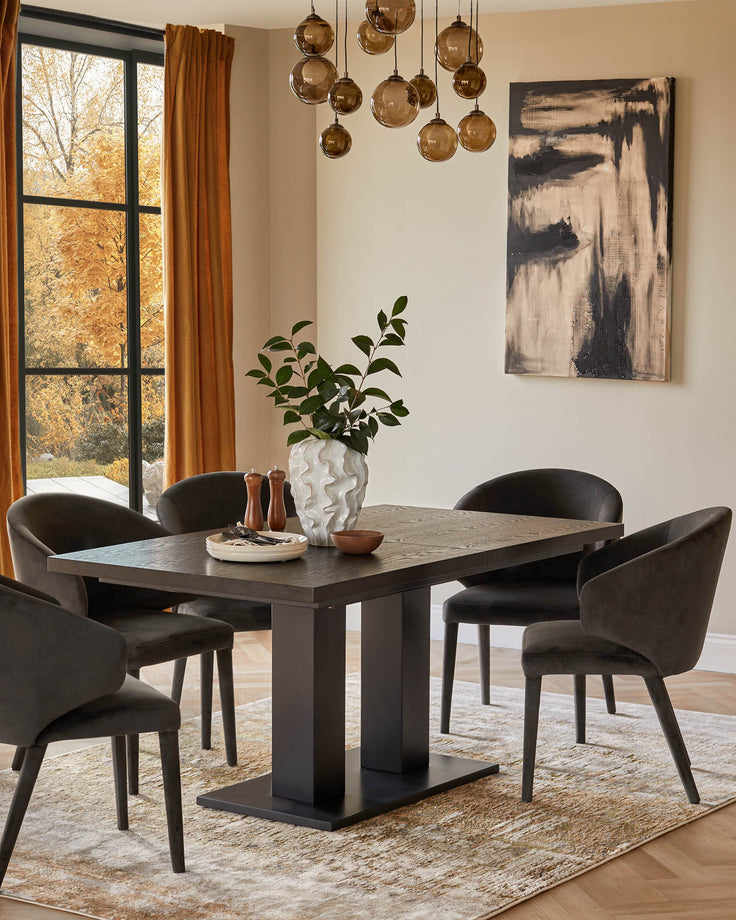 Dining table with four chairs, decorative vase and overhead lighting in a stylish, neutral dining room.