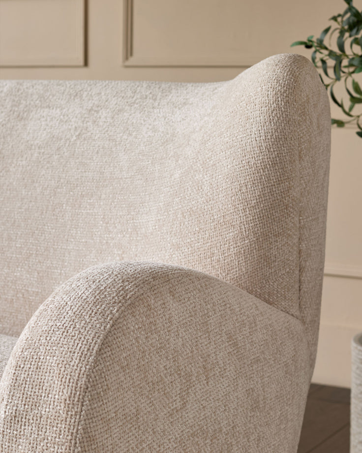 Evelyn 2-seater sofa in natural fabric, close-up of curved armrest and backrest detail.