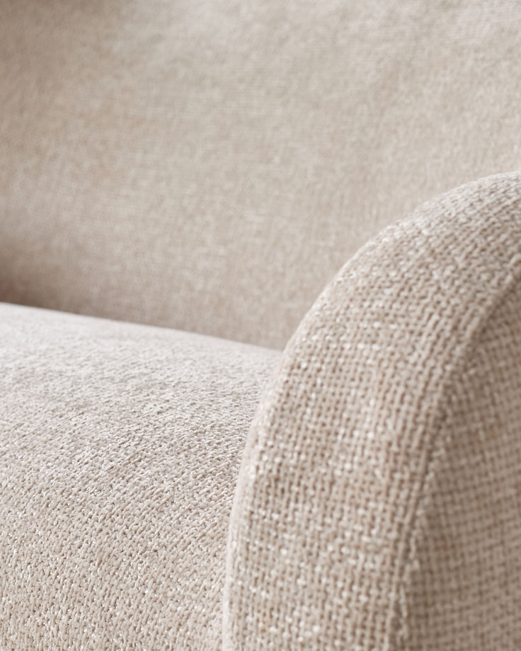 Close-up detail of natural beige fabric on Evelyn 3-seater sofa, showing textured weave and curved armrest.