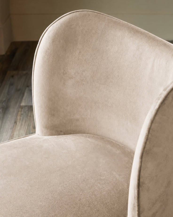 Evelyn Dining Chair in Champagne Velvet, showing curved backrest and seat cushion from side angle.