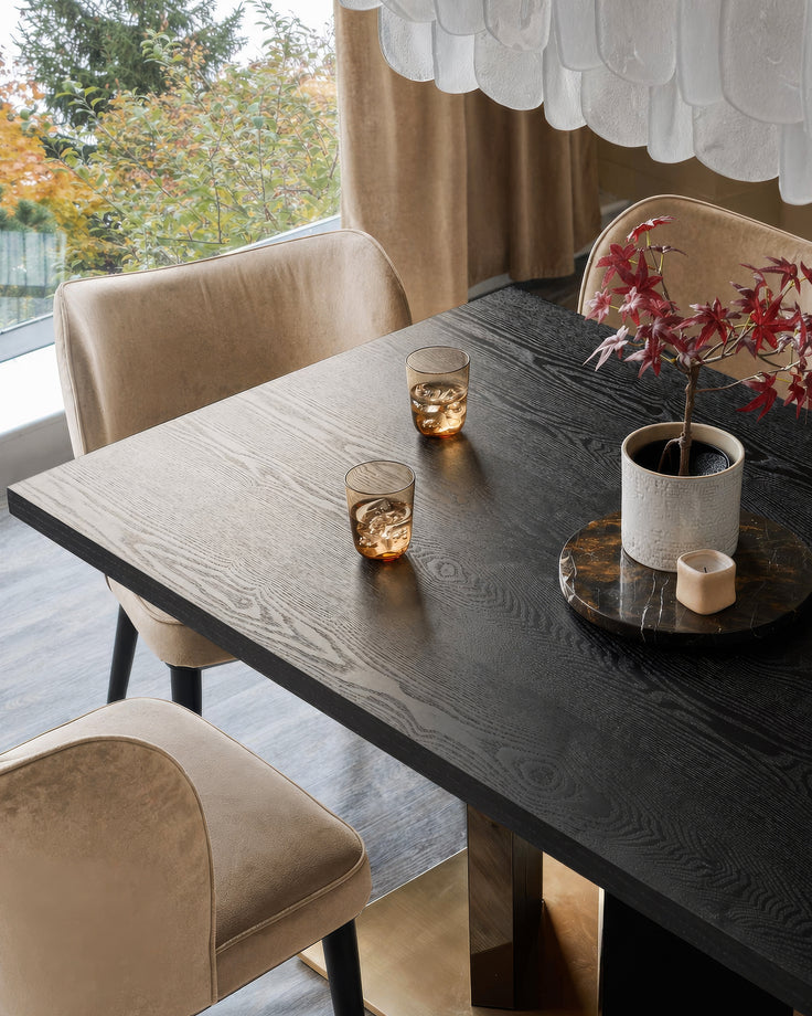 Evelyn dining chair in champagne velvet with black wooden legs, shown at dark wood table in modern dining room setting.