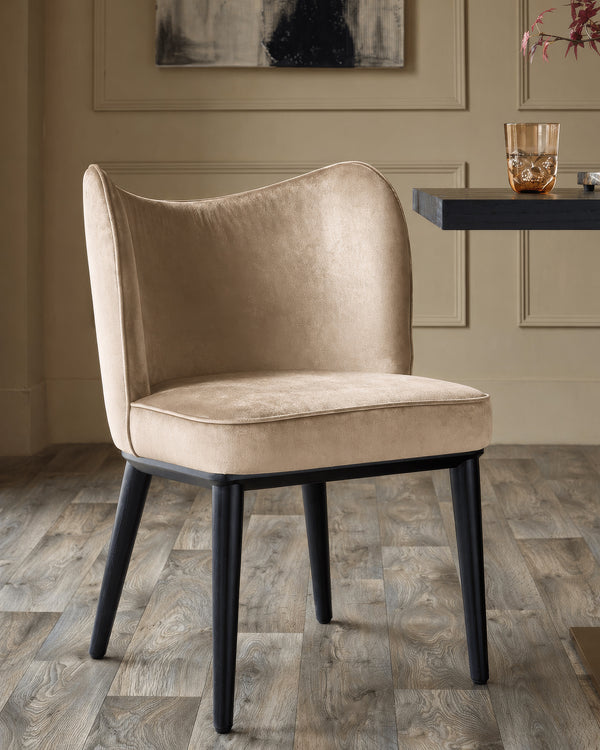 Evelyn dining chair in champagne velvet with black wooden legs, shown in a styled interior setting.