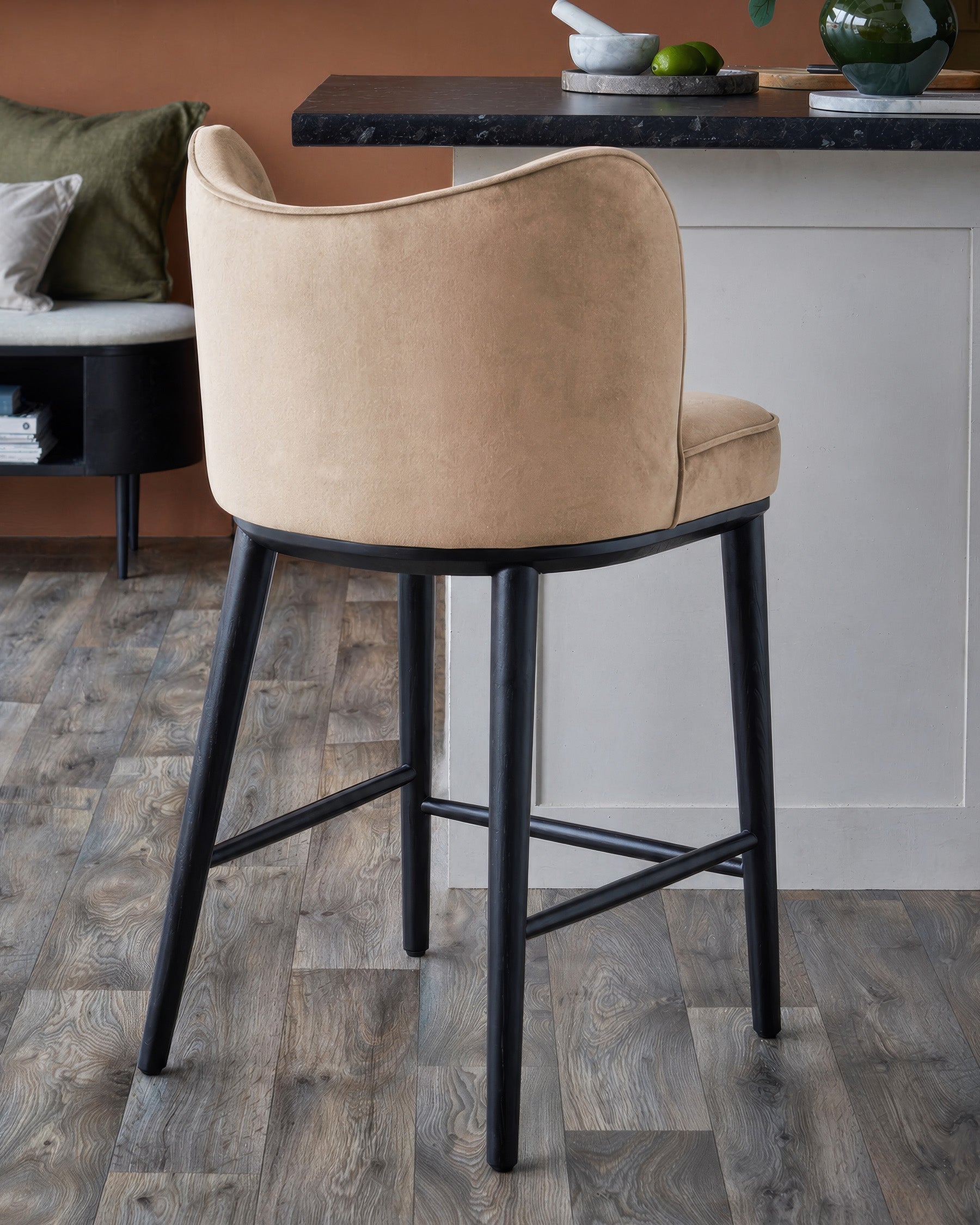 Evelyn bar stool in champagne velvet with black wooden legs, shown from back angle at counter height.