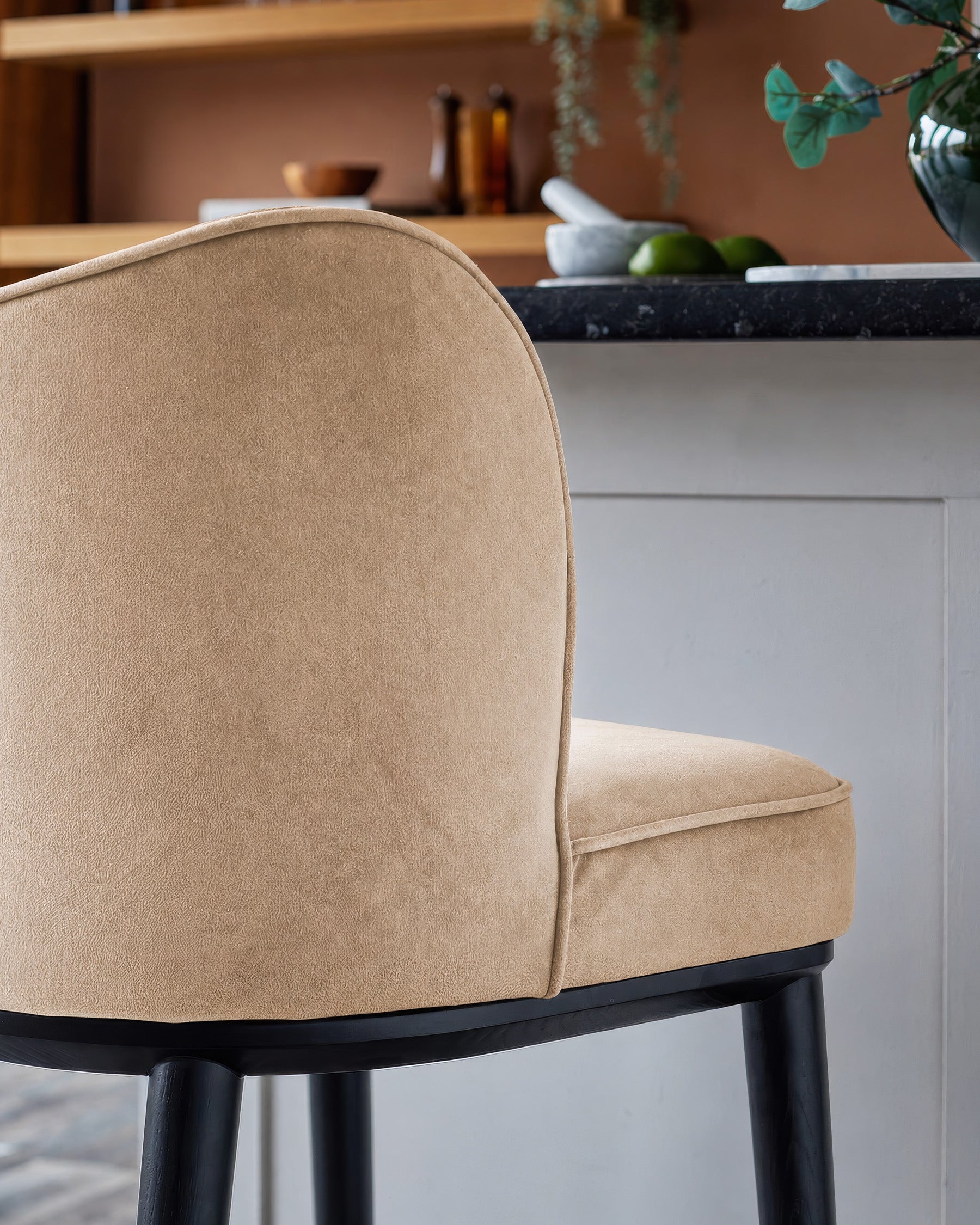 Evelyn bar stool in champagne velvet with black wooden legs, side view showing curved backrest and seat detail.
