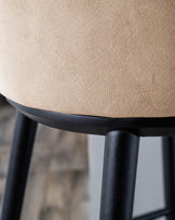 Evelyn bar stool with black wooden legs and champagne velvet seat, close-up detail view.