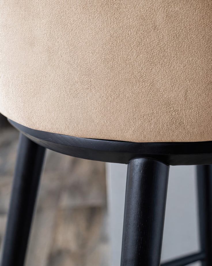 Evelyn bar stool with black wooden legs and champagne velvet seat, close-up detail view.