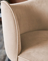 Champagne velvet bar stool with curved backrest and piping detail, close-up side view.
