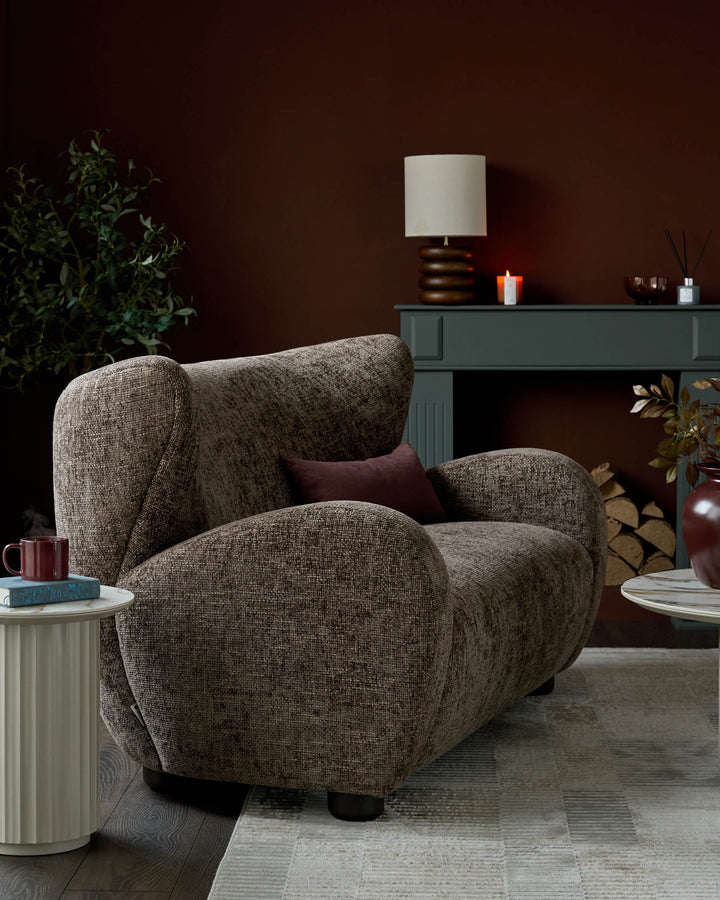 Evelyn 2-seater sofa in mocha fabric with curved arms and burgundy cushion, styled in a warm interior setting.