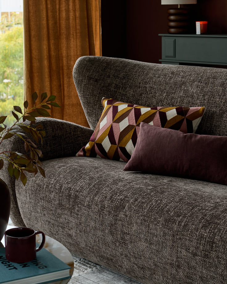 Evelyn 2-seater sofa in mocha fabric with decorative patterned and solid pillows, shown in a styled living room setting.