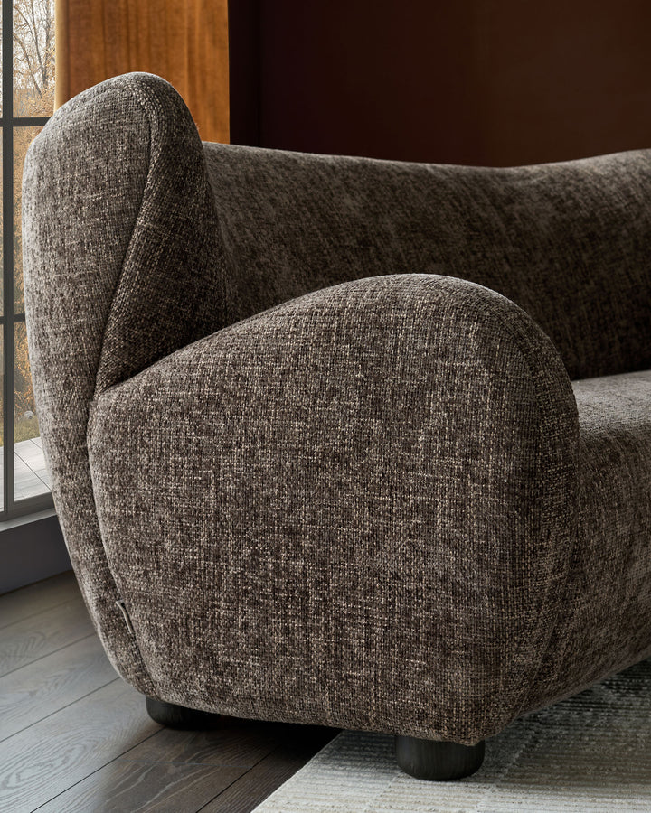 Evelyn 3-seater sofa in mocha fabric, showing curved armrest and seat detail from side angle.