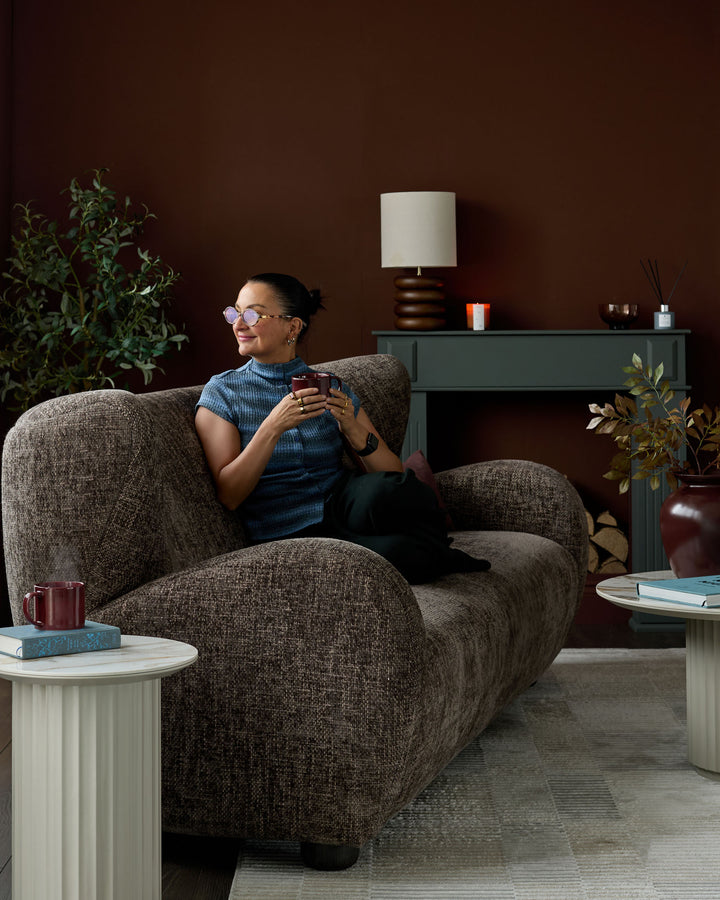Mocha fabric three-seater sofa with curved, rounded arms in a styled living room setting.