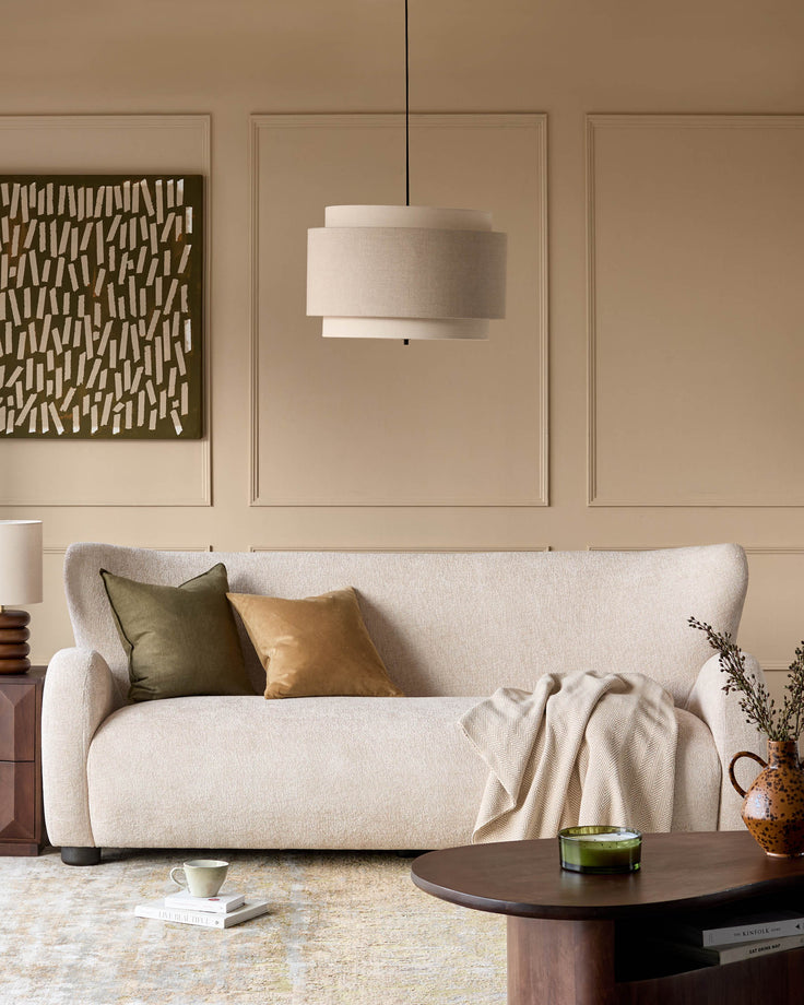 Evelyn 3-seater sofa in natural fabric, curved design with rolled arms, styled in a neutral living room setting.