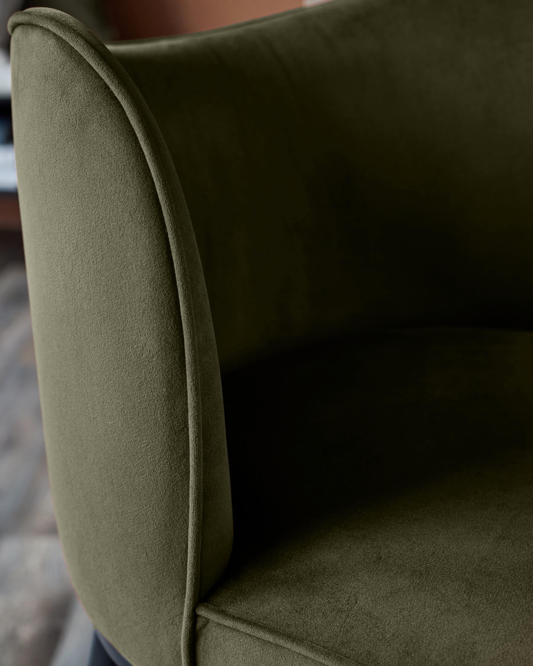 Close-up of a stylish armchair in olive green velvet, showcasing its soft texture and elegant design.