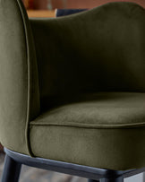 Close-up of an olive green velvet chair with a black frame, showcasing its texture and elegant design.