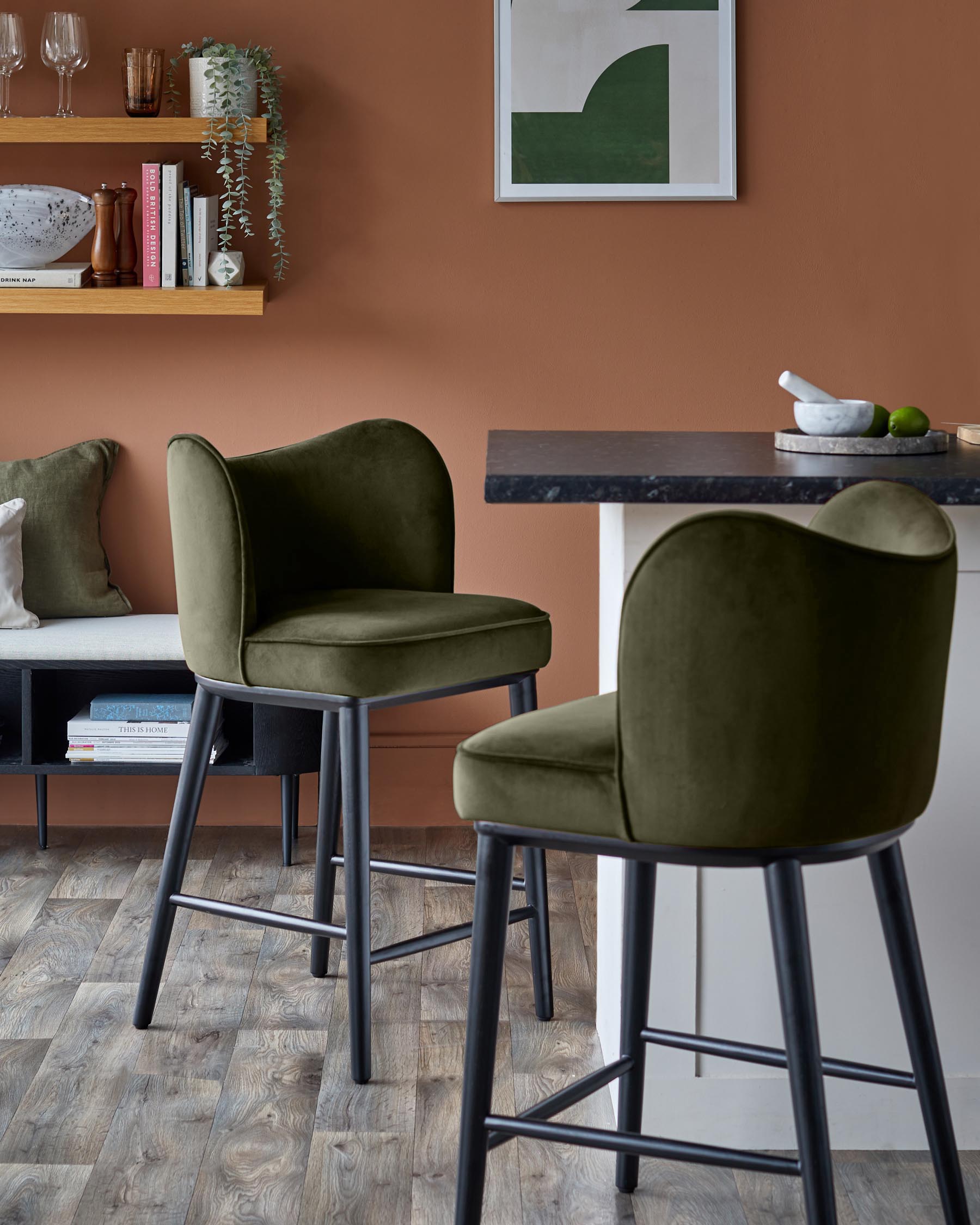 Two green velvet bar stools with black legs sit at a kitchen counter, creating a stylish, modern look.