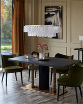 Dining room set with a dark table, green velvet chairs, and a modern chandelier. Side table in background.