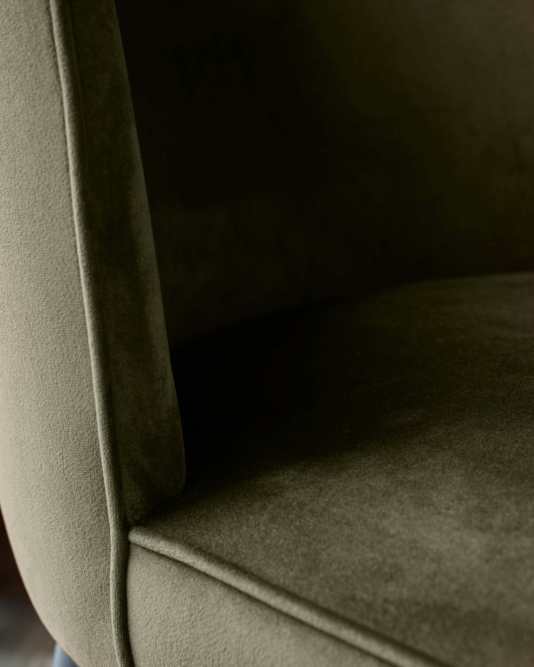 Close-up of an olive green armchair, showcasing its textured upholstery and curved frame.