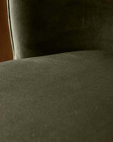 A close-up of a green upholstered chair, showcasing its soft texture and design. Ideal for adding comfort to any room.
