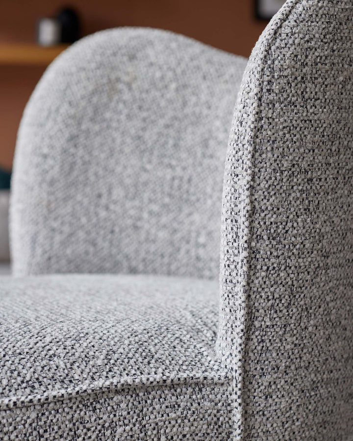Close-up of a grey textured armchair, showcasing the fabric and detailing.