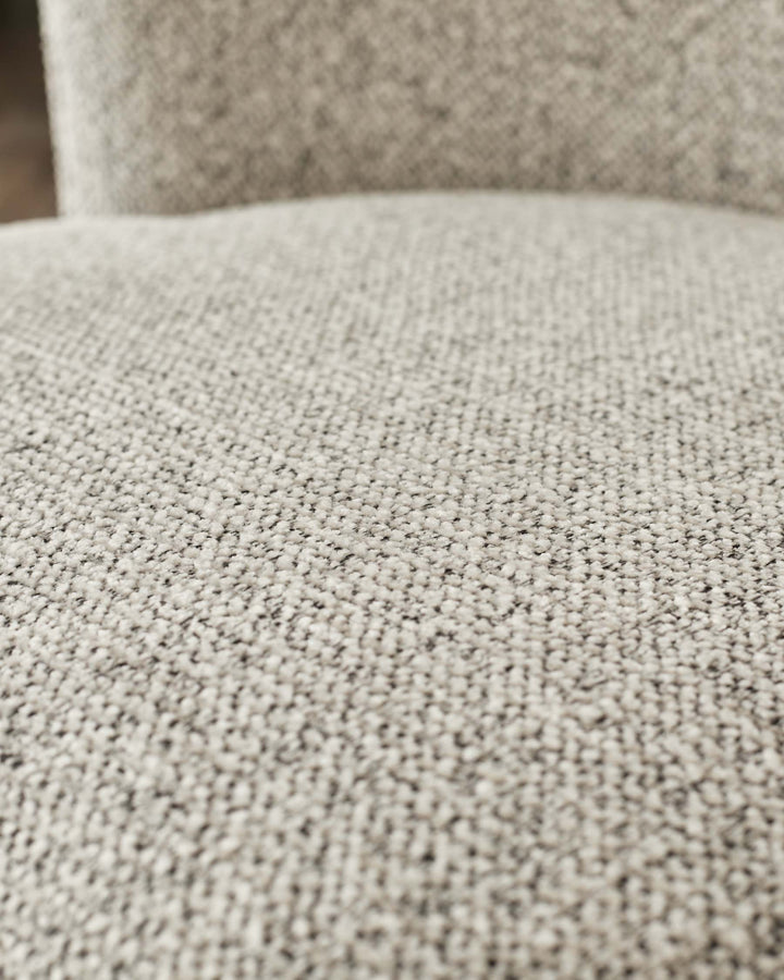 Close-up of a light grey tweed-like sofa cushion showing the woven texture of the fabric.