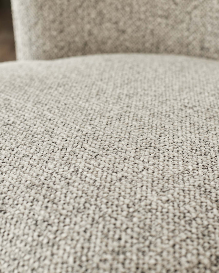Close-up of a light grey tweed-like sofa cushion showing the woven texture of the fabric.