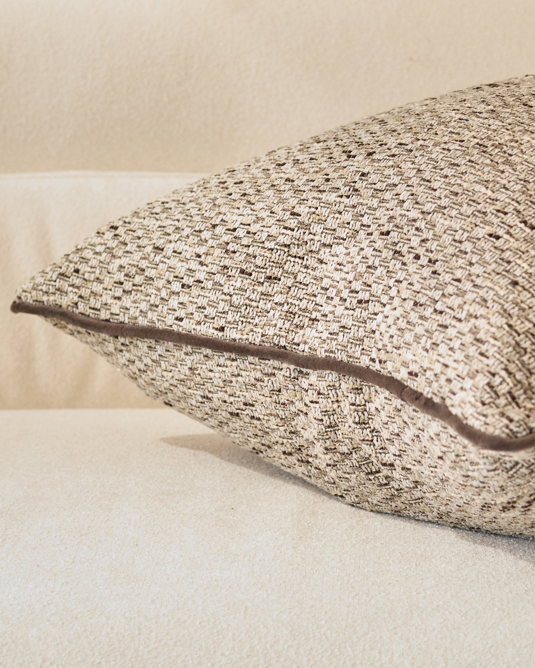 Fabian large cushion in natural beige, showing textured woven fabric detail from a side angle.