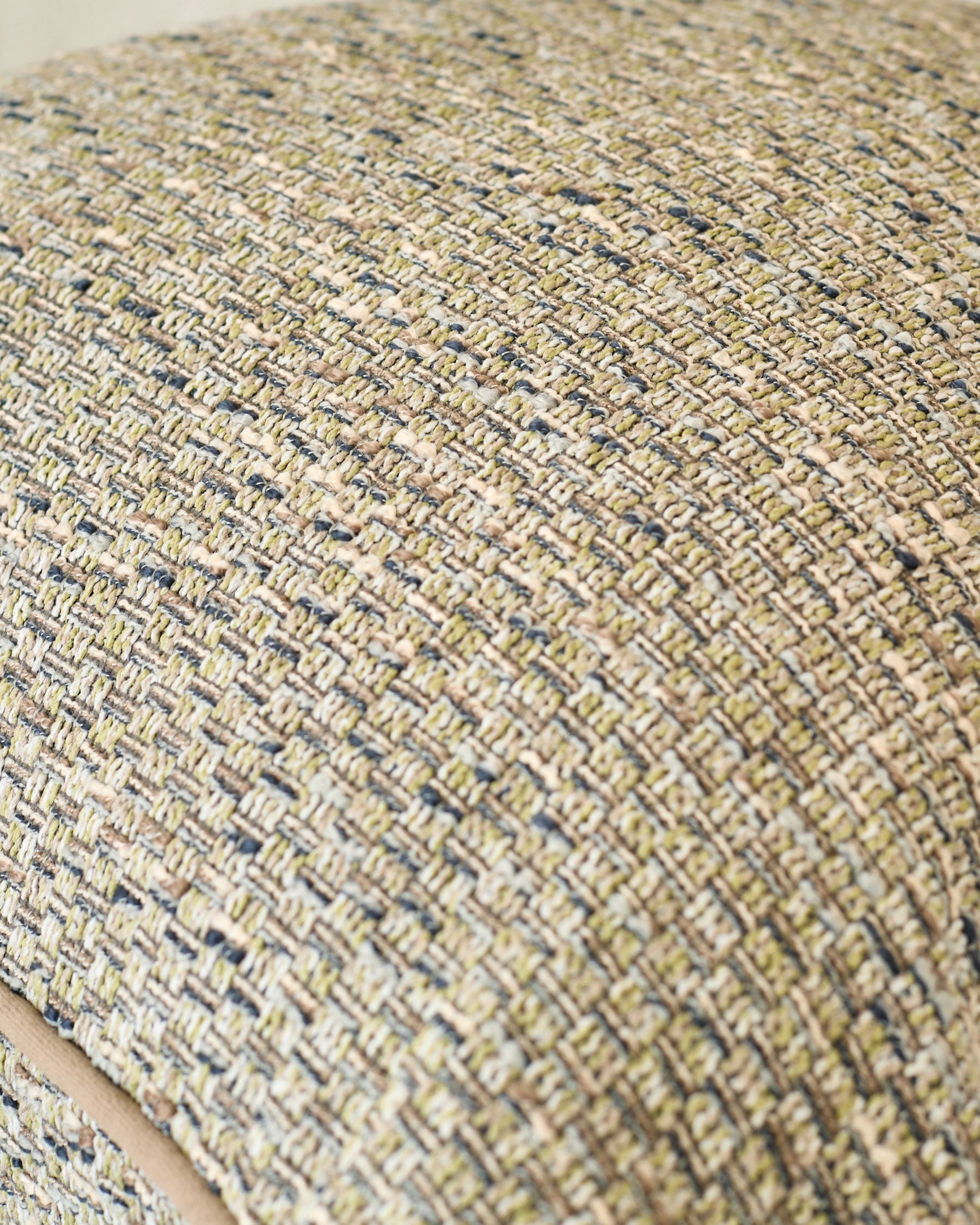 Close-up of Fabian large green cushion showing textured woven fabric with neutral and blue-toned yarns in a basket weave pattern.