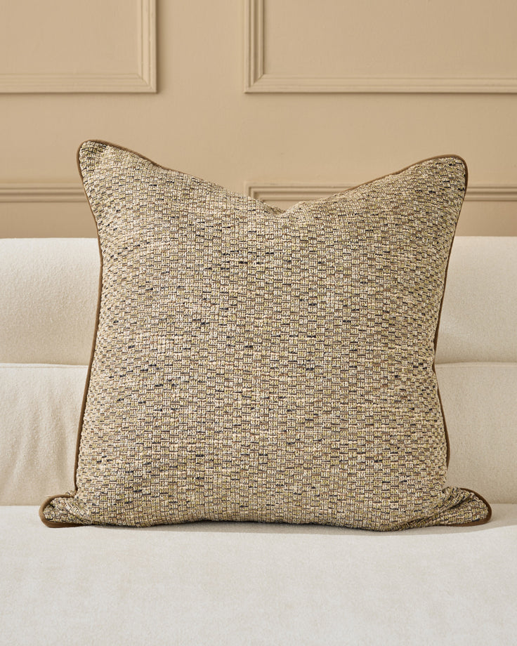 Large square cushion in neutral beige textured fabric with piping detail, displayed on a cream upholstered sofa.
