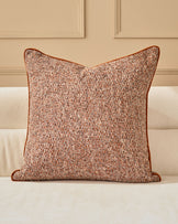 Fabian cushion in rust with textured weave, displayed on a cream sofa against a neutral wall with paneling.