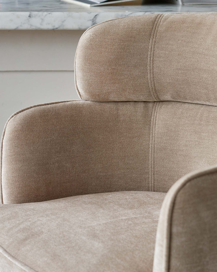 Close-up of a beige upholstered chair, showcasing the textured fabric and subtle stitching details.