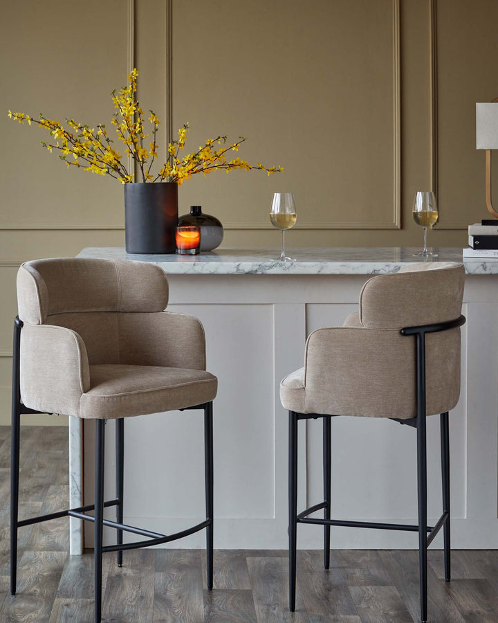 Two upholstered bar stools with dark metal legs stand beside a breakfast bar with a marble countertop.