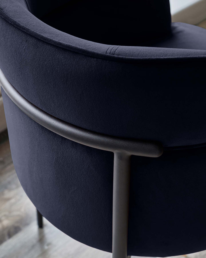 Close-up of a stylish, navy velvet chair with sleek metal frame. Modern and inviting.