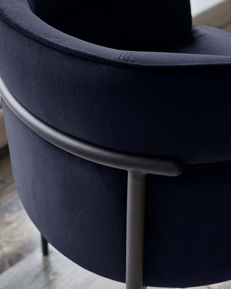 Close-up of a stylish, navy velvet chair with sleek metal frame. Modern and inviting.