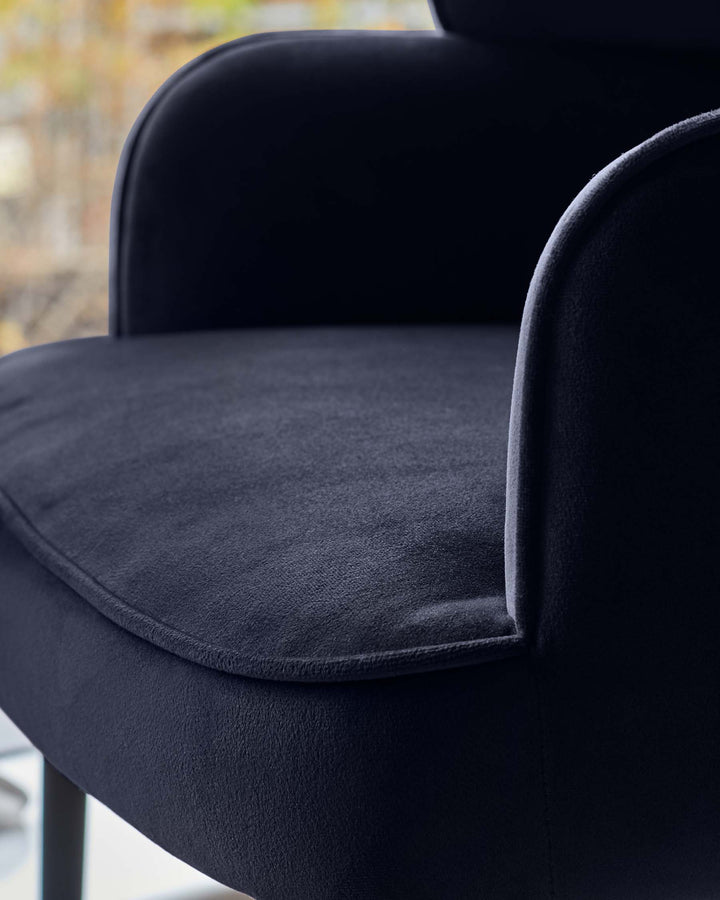 Close-up of a stylish, dark-upholstered chair with curved armrests, showcasing its plush texture and modern design.