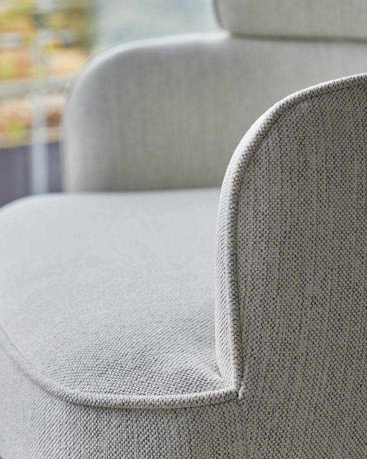 Close-up of a stylish, light grey, textured fabric armchair. Comfortable and modern seating for your home.