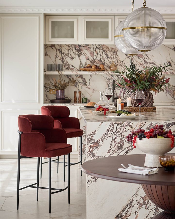 Felix bar stool in toffee red velvet with black metal frame, shown in modern kitchen setting.