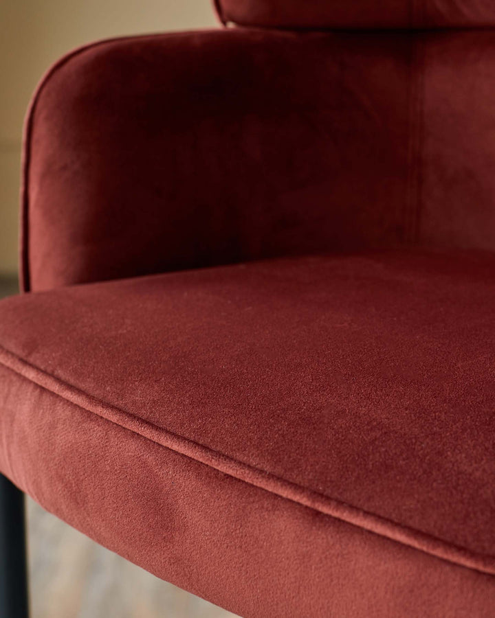 Close up of a stylish, modern chair with a plush, burgundy velvet seat and backrest. Ideal for adding a touch of luxury to any space.