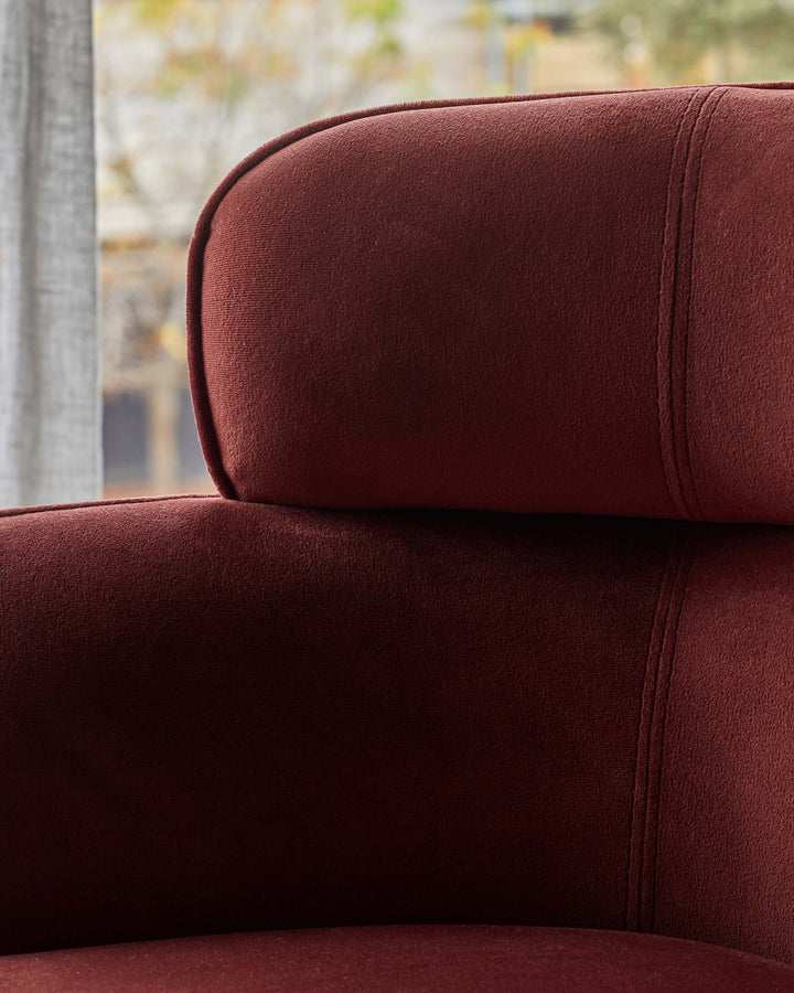 Close up of a burgundy coloured upholstered sofa, with a seam detail.