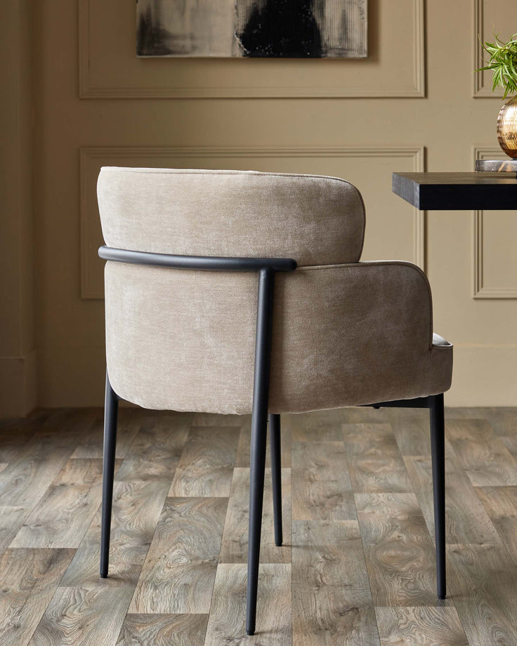 Stylish chair with a curved back, upholstered in a neutral fabric and black metal legs. Modern design for the dining room.