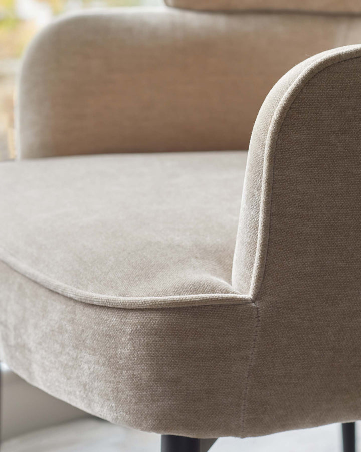Close up of a beige chair with curved arms. Neutral colour scheme. Simple design perfect for modern interiors.