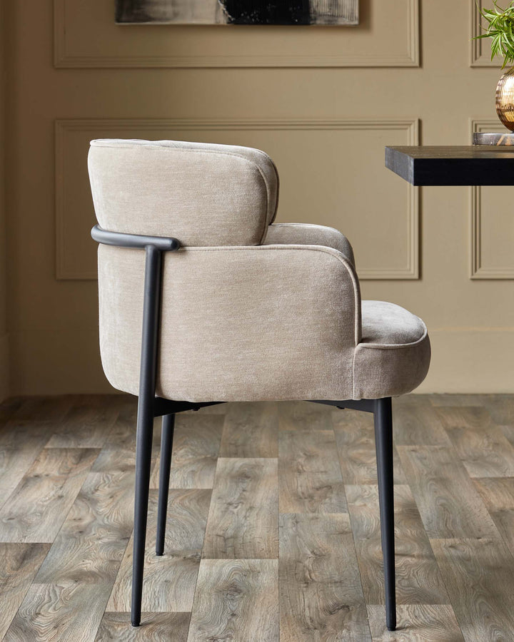 A stylish, beige upholstered dining chair with black metal frame, sitting on a wood floor.