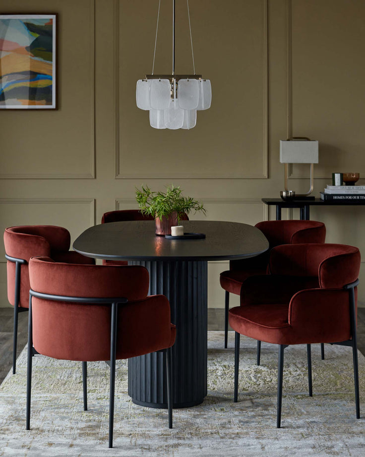 Dining area with a round table, five rust-coloured velvet chairs, a modern pendant light, and abstract art.