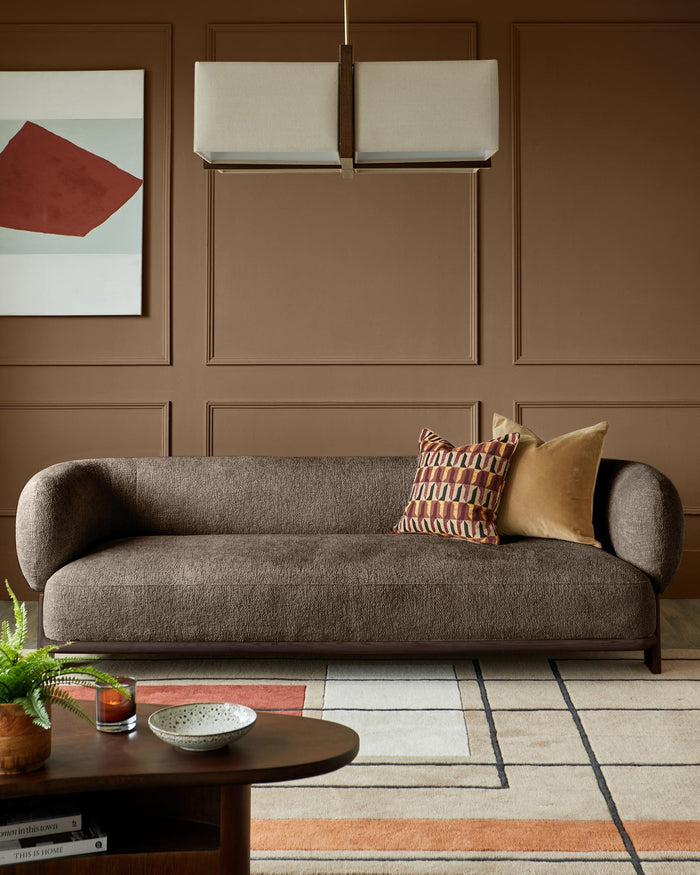 Brown sofa with cushions, coffee table and overhead light, creating a warm, inviting living space.