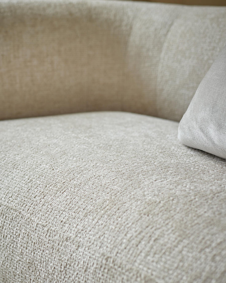 Close up of a neutral coloured sofa with a textured fabric and a grey cushion.