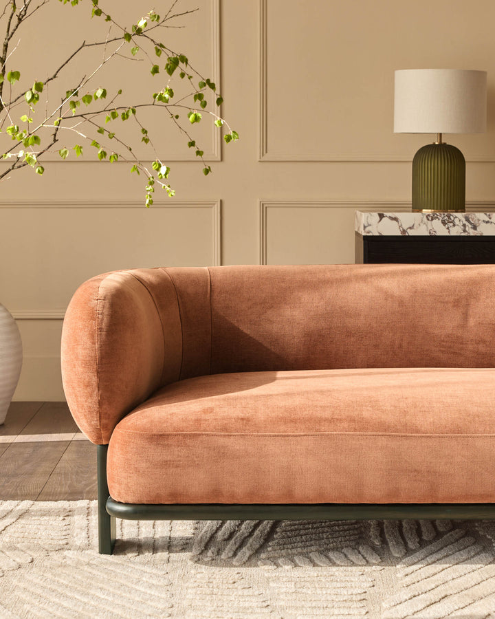 Florence 2-seater sofa in apricot fabric with dark wood base, shown in a styled living room setting.